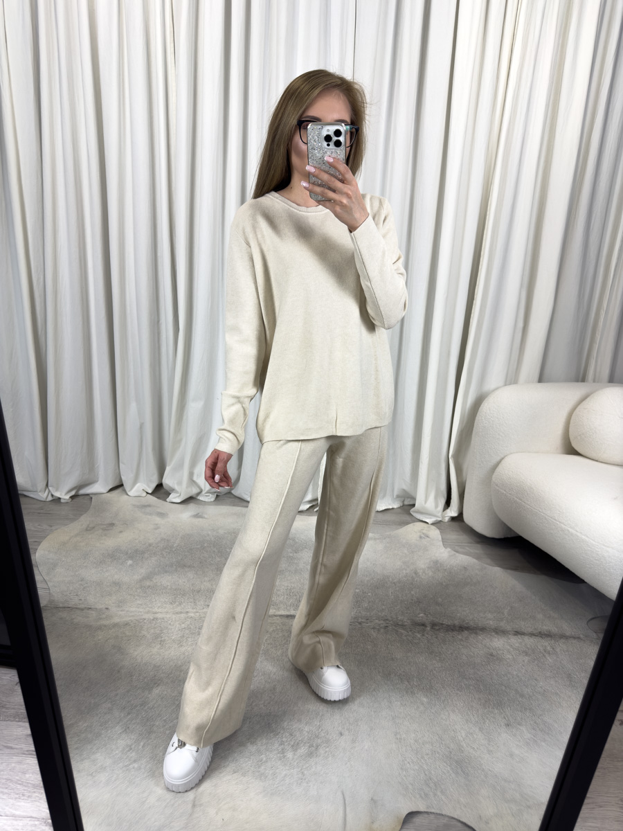 IMG_3425 Komplet dzianinowy Comfy kremowy – luźna bluza i proste spodnie, stylizacja z białymi sneakersami na tle jasnego wnętrza.
