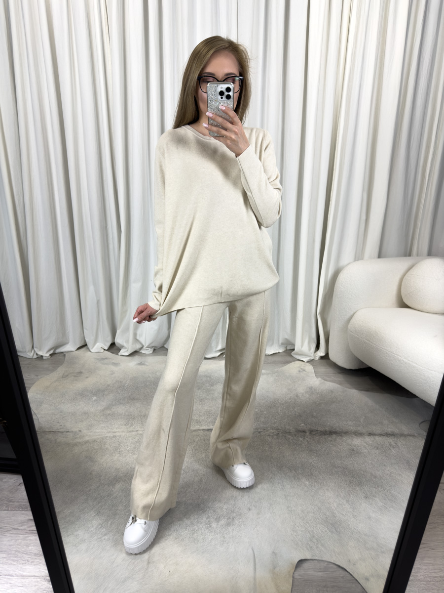 IMG_3431 Komplet dzianinowy Comfy kremowy – luźna bluza i proste spodnie, stylizacja z białymi sneakersami na tle jasnego wnętrza.