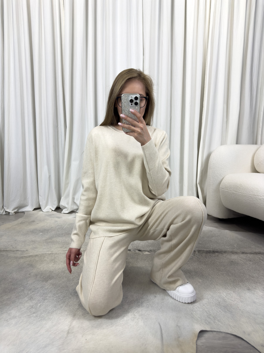 IMG_3435 Komplet dzianinowy Comfy kremowy – luźna bluza i proste spodnie, stylizacja z białymi sneakersami na tle jasnego wnętrza.