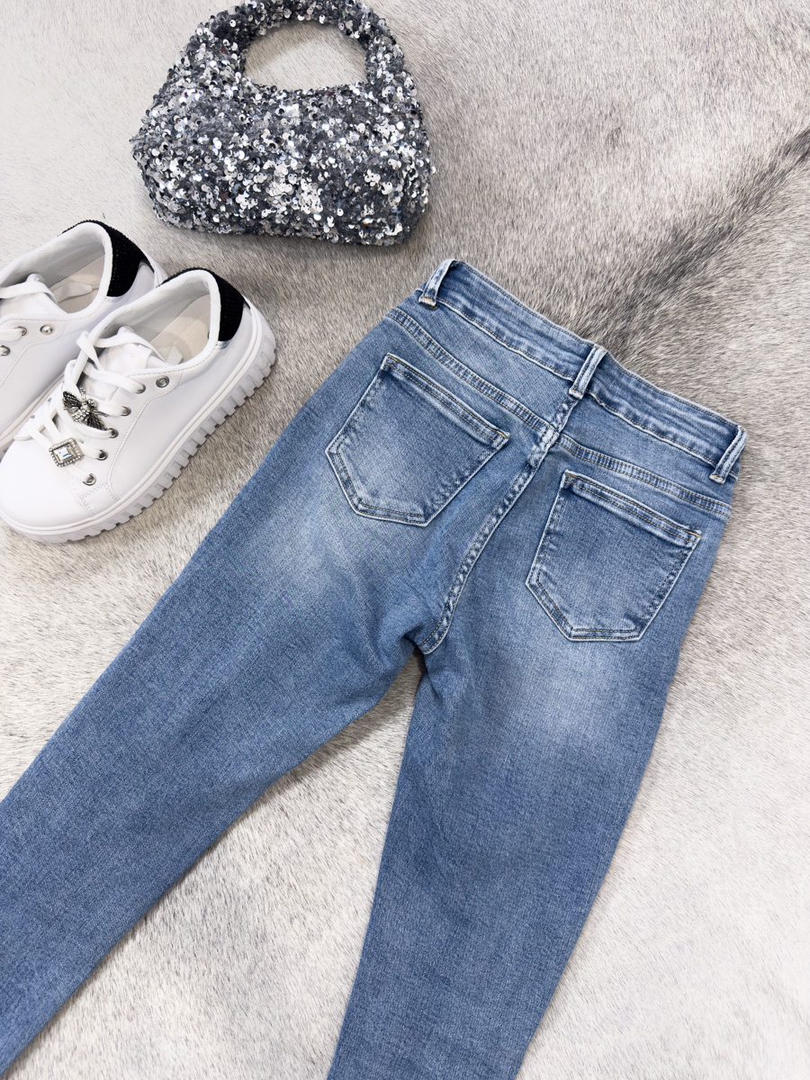 IMG_7131 Spodnie jeansowe skinny Malibu – dopasowane niebieskie jeansy damskie z przetarciami i surowym wykończeniem nogawek, stylizacja z T-shirtem i sneakersami.