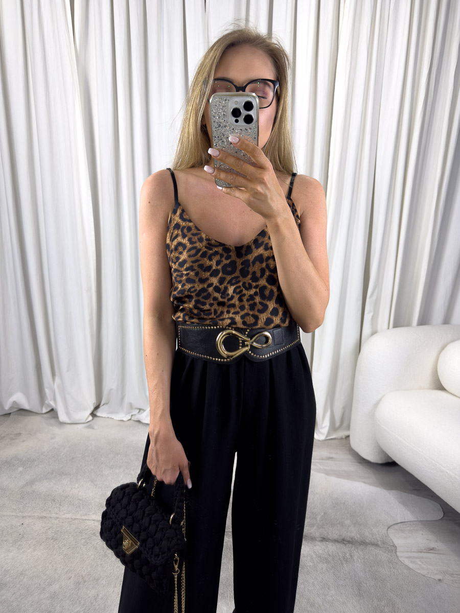 top-satynowy-animal-print-4 Zdjęcie produktowe sklepu internetowego z odzieżą damską – modelka ubrana w top satynowy Animal Print, czarne spodnie palazzo, trzymająca w ręce małą czarną torebkę