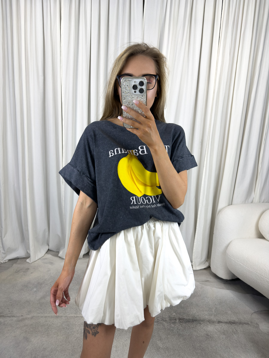 IMG_2936 Modelka w dekatyzowanym T-shircie z nadrukiem banana i białej spódniczce – stylizacja z przymrużeniem oka, casualowa i dziewczęca.
