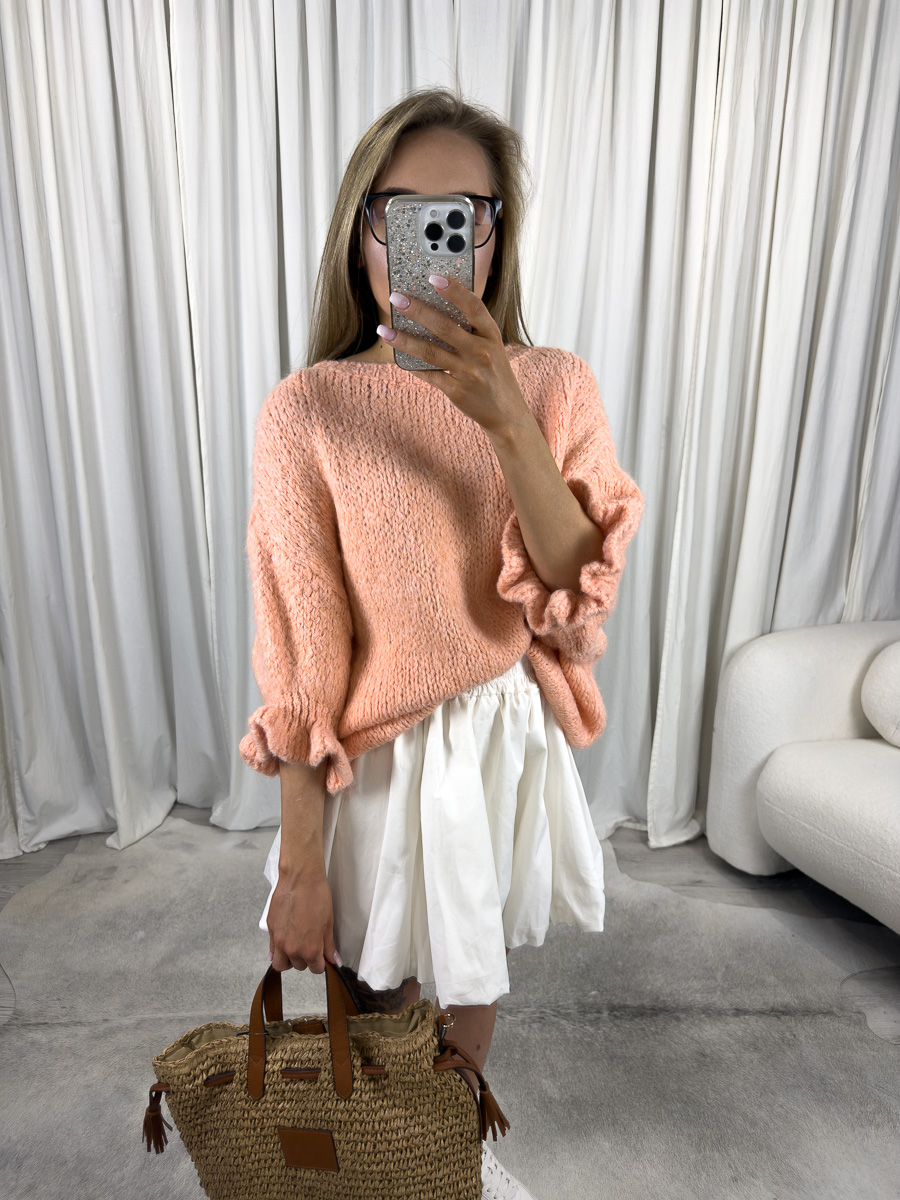 IMG_2971 Kobieta w swetrze pastelowym Flounce pomarańczowym z falbanką i białą spódnicą, z plecioną torbą – stylizacja casual boho.