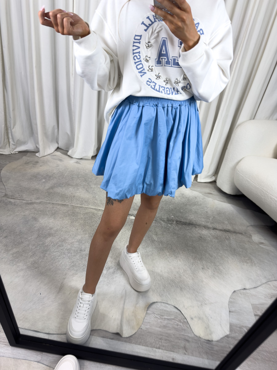 mini-spodnica-z-popeliny-cutie-blekitna Modelka w błękitnej mini spódnicy z popeliny Cutie o balonowym kroju i elastycznym pasie – stylizacja z bluzą oversize i sneakersami, zdjęcie produktowe na potrzeby sklepu internetowego.