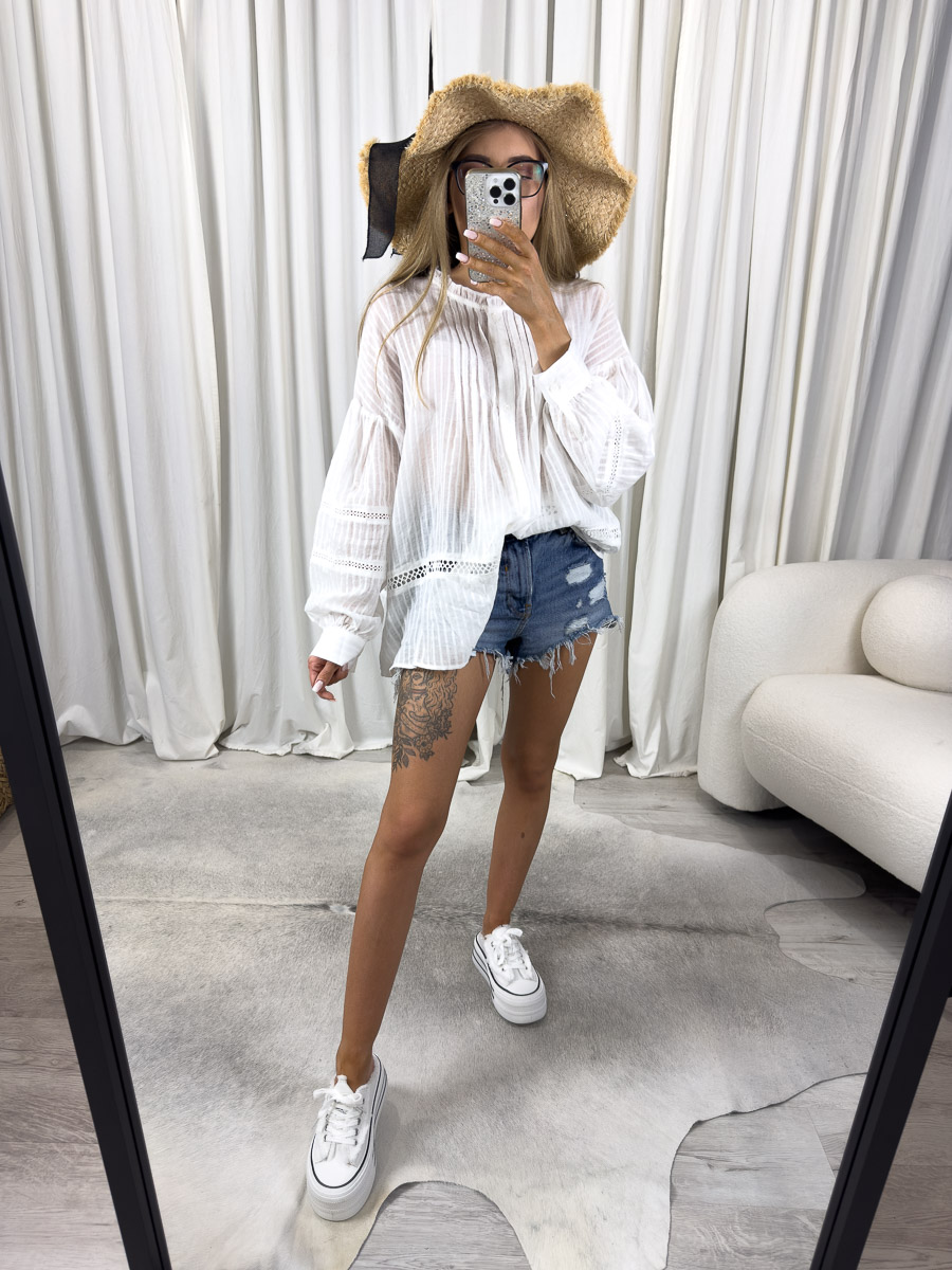 koszula-w-stylu-boho-luna-wiya Zdjęcie produktowe sklepu internetowego z odzieżą damską – modelka w koszuli boho Luna marki Wiya, zestawionej z jeansowymi szortami, kapeluszem i wiklinową torbą