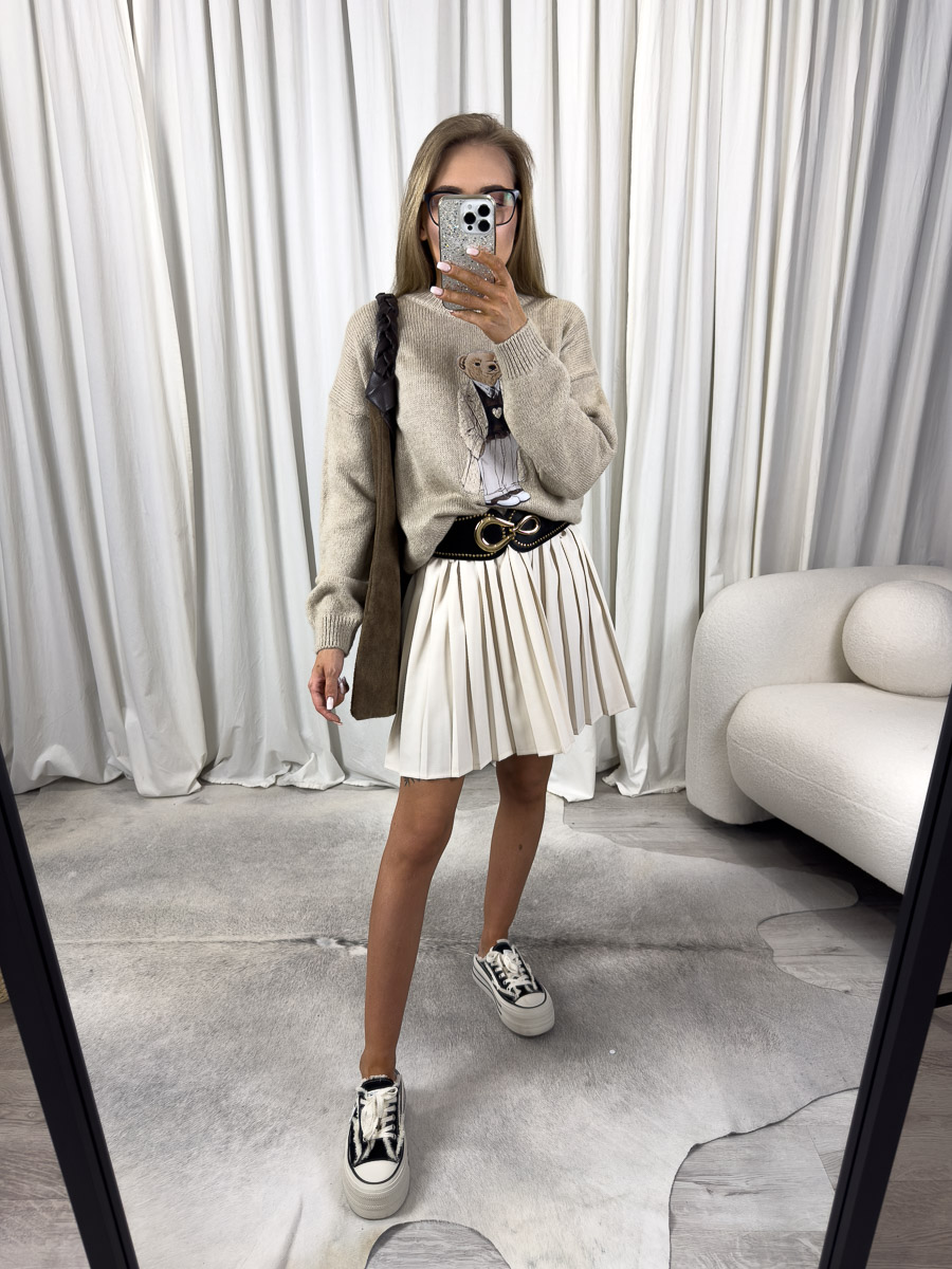sweter-teddy-bezowy-azara-3 Zdjęcie produktowe sklepu internetowego z odzieżą damską – modelka w trampkach ubrana w sweter Teddy beżowy, krótką plisowaną spódnicę