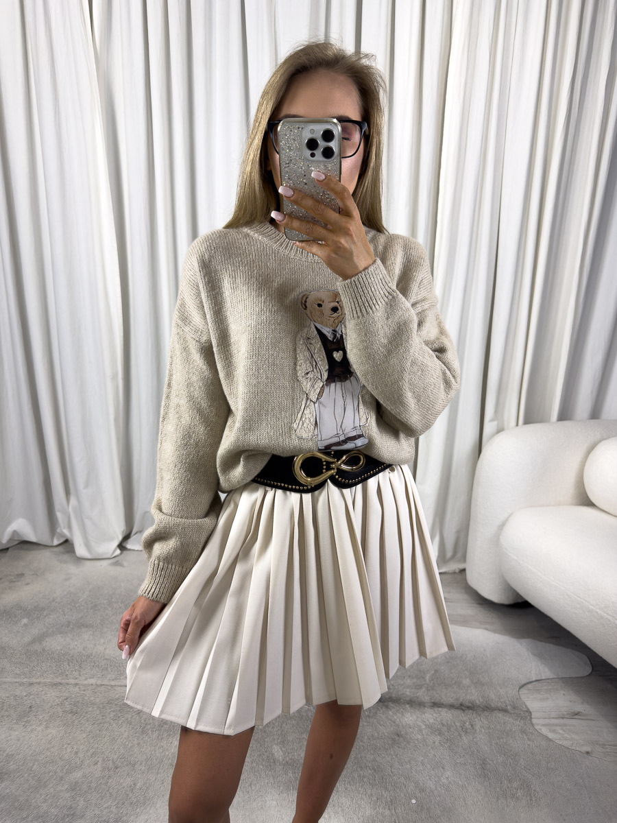 sweter-teddy-bezowy-azara-3 Zdjęcie produktowe sklepu internetowego z odzieżą damską – modelka w trampkach ubrana w sweter Teddy beżowy, krótką plisowaną spódnicę