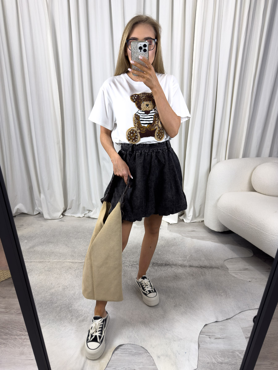 t-shirt-teddy-bialy Zdjęcie produktowe sklepu internetowego z odzieżą damską – modelka w trampkach ubrana w t-shirt Teddy biały, spódnicę w kolorze dekatyzowanej czerni trzymająca w ręce zamszową torebkę